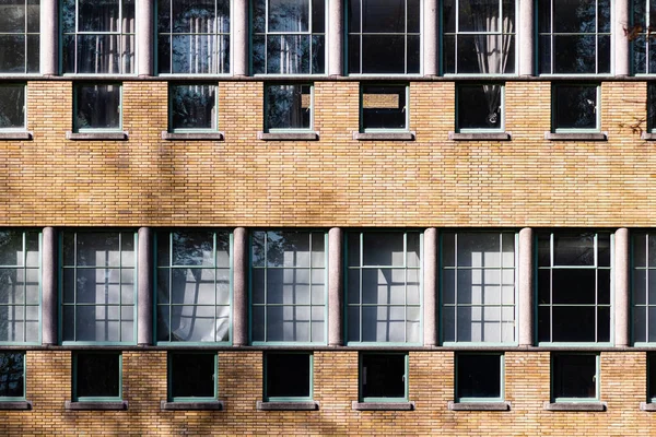 Sun reflects in the steel windows of an old brick school building. High-quality photo