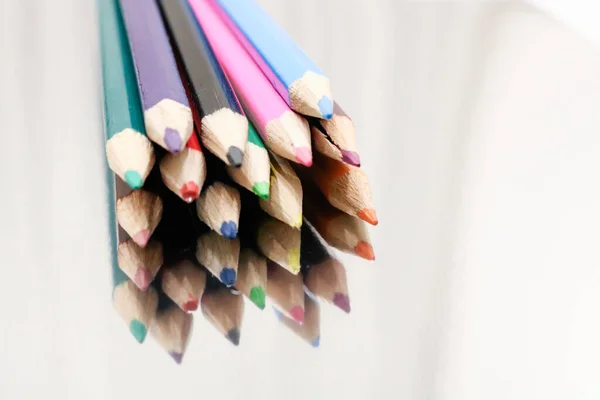 close-up picture of twelve colour pencils isolated on a neutral background indoors. facing the sharpened points of the pencils and fading into a blur at the end.