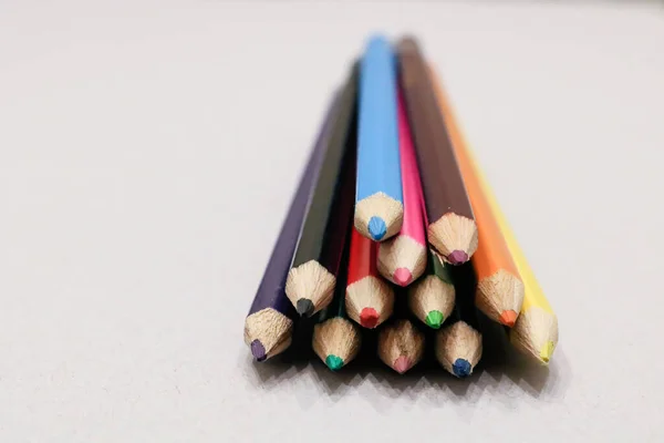 close-up picture of twelve colour pencils isolated on a neutral background indoors. facing the sharpened points of the pencils and fading into a blur at the end.
