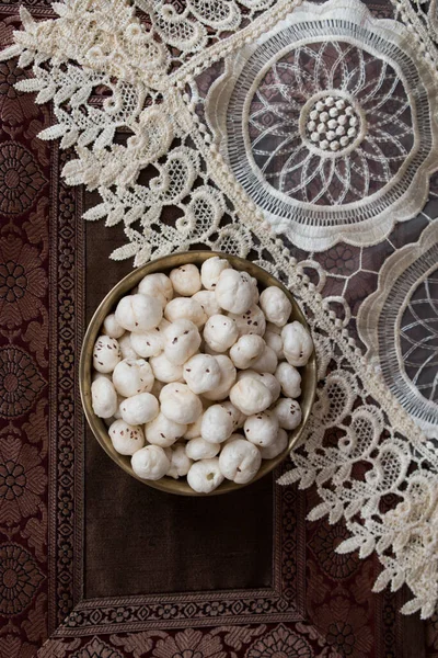 Crispy Lotus pops Seeds or Phool Makhana or Fox Nuts popular dry snacks from India served in a brass bowl. Top view. Makhana from Mithila region of Bihar in India. Mithilanchal. selective focus