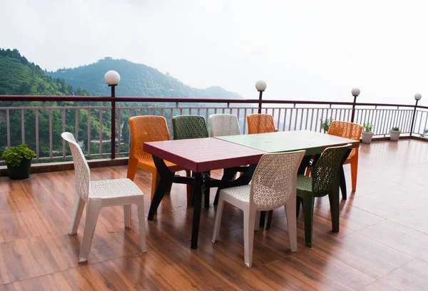 Empty Dining table chair set at the Mountain or Hill view with rainy day. wooden floor.