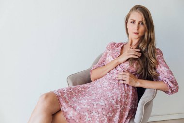 Açık arkaplanda pembe elbiseli güzel sarışın kadın.