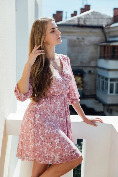 Hermosa mujer rubia en vestido rosa en el balcón mirando fuera —  Fotos de Stock