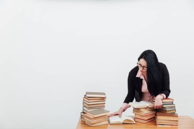 Takım elbiseli güzel esmer kadın masada kitap okumayı öğreniyor.