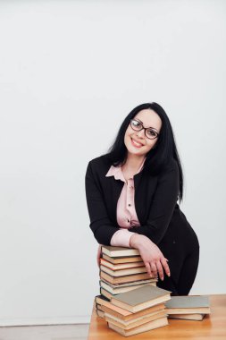 Masasında kitapları olan takım elbiseli güzel esmer kadın.