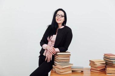 Masasında kitapları olan takım elbiseli güzel esmer kadın.