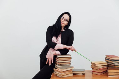 Masasında kitapları olan takım elbiseli güzel esmer kadın.