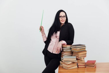 Bir sürü kitabı olan takım elbiseli bir esmer kadın.