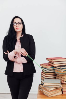 Bir sürü kitabı olan takım elbiseli bir esmer kadın.