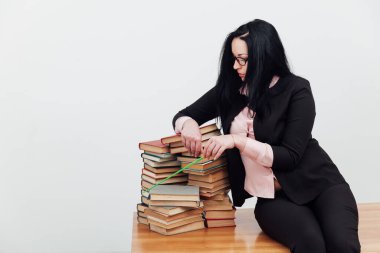 Bir sürü kitabı olan takım elbiseli bir esmer kadın.