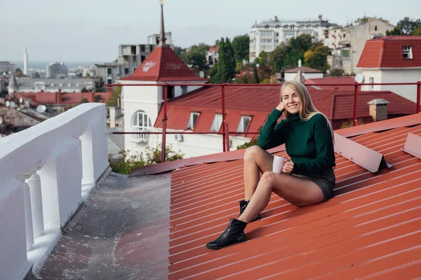 Güzel bir kadın, sarışın ve evin çatısından kahve şehri. — Stok fotoğraf