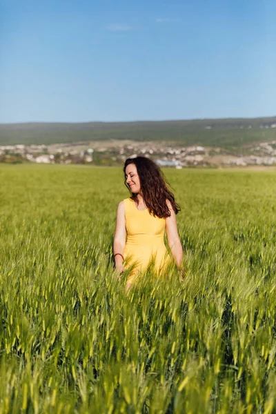 Mooie brunette vrouw in een veld van groene tarwe — Stockfoto
