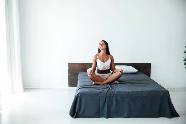 Bela mulher de linho sentado na cama no quarto — Fotografia de Stock