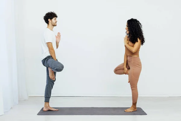 Eine Frau und ein Mann praktizieren in einem weißen Raum ein paarweißes Yoga-Asana — Stockfoto