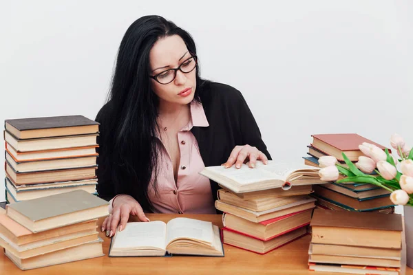 Hermosa morena en un traje de negocios aprende a leer libros en la mesa — Foto de Stock