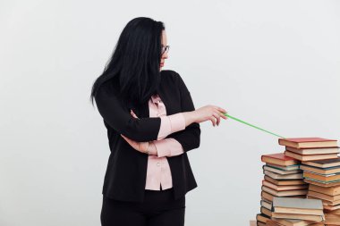 Bir sürü kitabı olan takım elbiseli bir esmer kadın.