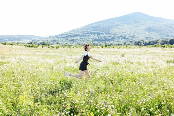 Tarlada papatyalarla koşan elbiseli güzel bir kadın.