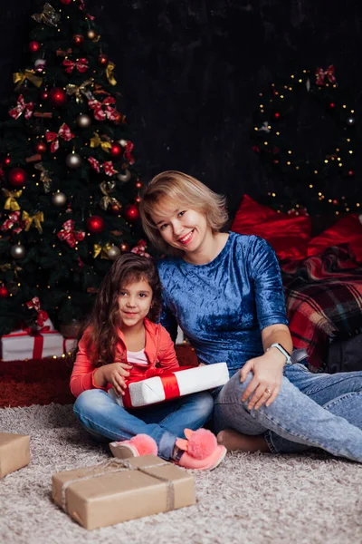 Мать и дочь открывают подарки на новогоднюю елку — стоковое фото