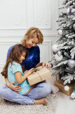 Anne ve kızı yeni yıl için Noel ağacında hediyeler açıyor.