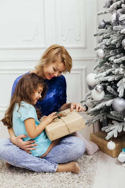 Anne ve kızı yeni yıl için Noel ağacında hediyeler açıyor.