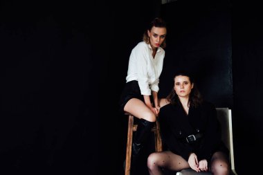 Beyaz ve siyah giysiler içinde yan yana iki kadın arkadaş.