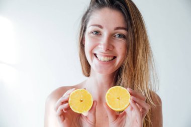 Güzel bir kadın elinde iki sarı limon tutuyor.