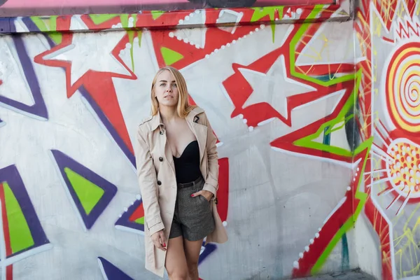 Piękna blondynka w płaszczu przeciwdeszczowym spaceruje ulicami miasta — Zdjęcie stockowe