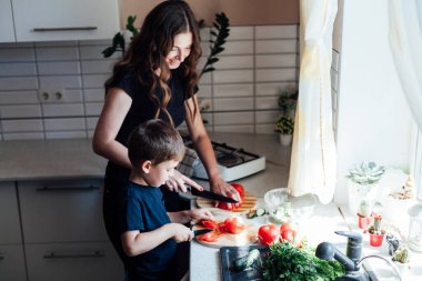 Anne ve oğlu mutfakta öğle yemeğinde salata için taze sebze hazırlıyorlar.