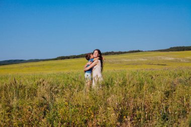 Anne tarlada yürürken oğluna sarılıyor.