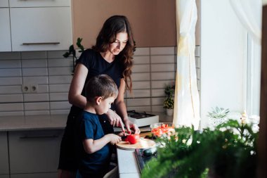 Anne ve oğlu mutfakta öğle yemeğinde salata için taze sebze hazırlıyorlar.