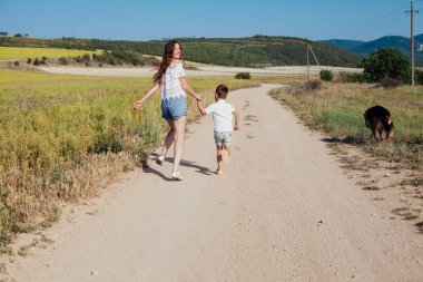 Bir çocuk ve köpeği olan bir anne yürüyüş için yolda koşuyorlar.