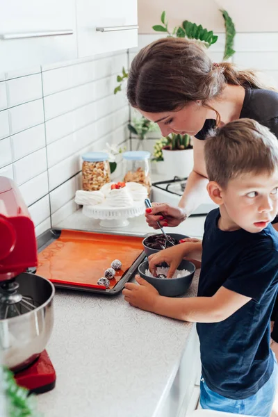 Eine Frau mit ihrem Sohn kocht köstliche süße Desserttorten in der Küche — Stockfoto