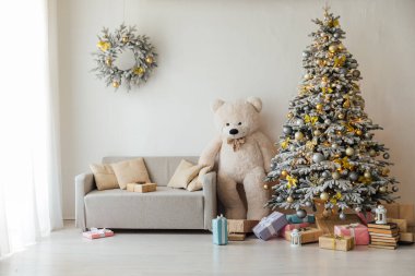 Hediyelerle dolu beyaz Noel ağacı ve beyaz bir oyuncak ayı.