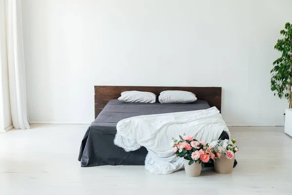 Інтер'єр білої спальні з ліжком і квітами — стокове фото