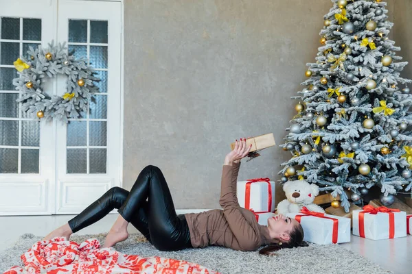 Красивая женщина открывает подарки на новогоднюю елку — стоковое фото