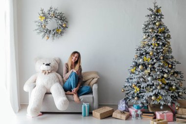 Beyaz Noel ağacının yanındaki kanepede yeni yıl hediyeleriyle güzel bir kadın.