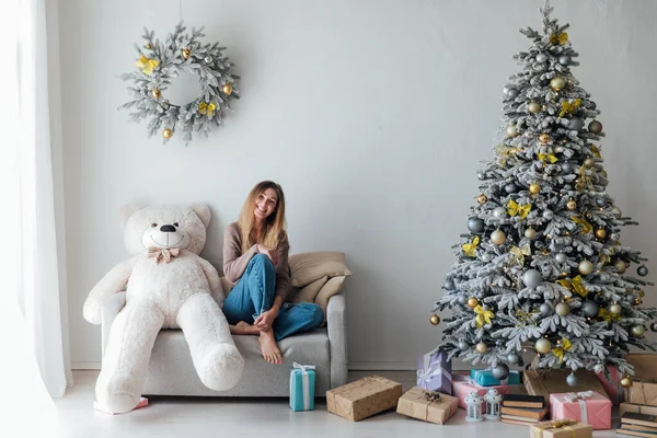 Beyaz Noel ağacının yanındaki kanepede yeni yıl hediyeleriyle güzel bir kadın.