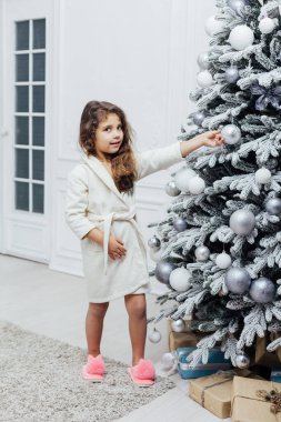 5 yaşındaki kız yılbaşı ağacını süslüyor.