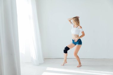 Sarışın atletik kadın tek başına müzikle dans ediyor.