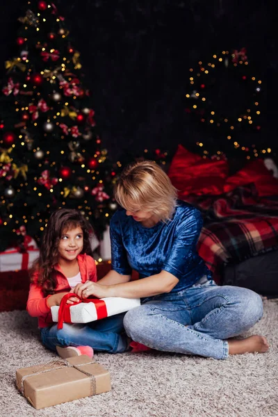 Мама маленькая девочка открывает подарки на новогоднюю елку — стоковое фото
