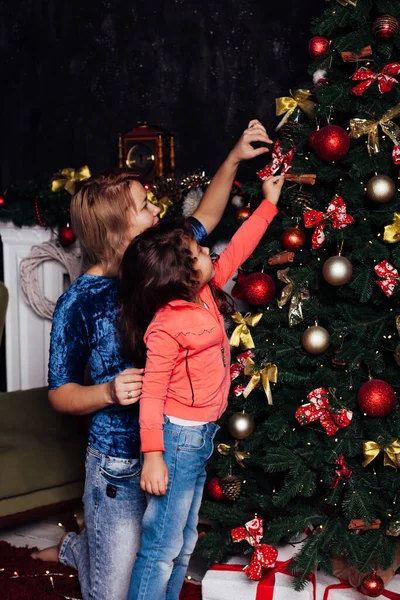 Мама и девочка украшают елки новогодние игрушки — стоковое фото
