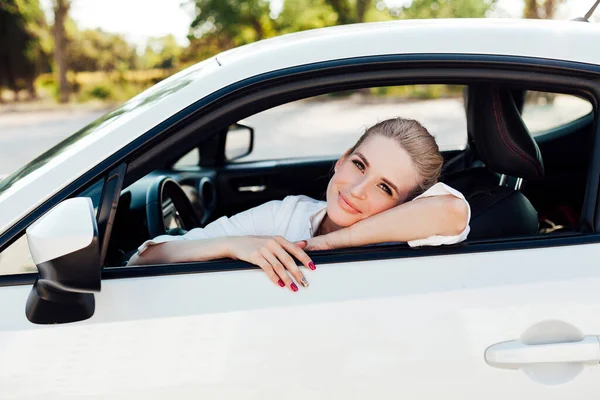 Bela mulher loira dirigindo um carro branco — Fotografia de Stock