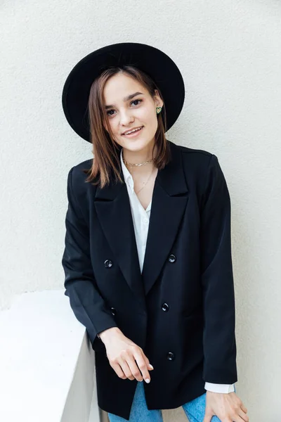 Portrait of a beautiful fashionable young woman in jeans and a black hat — Stock Photo, Image