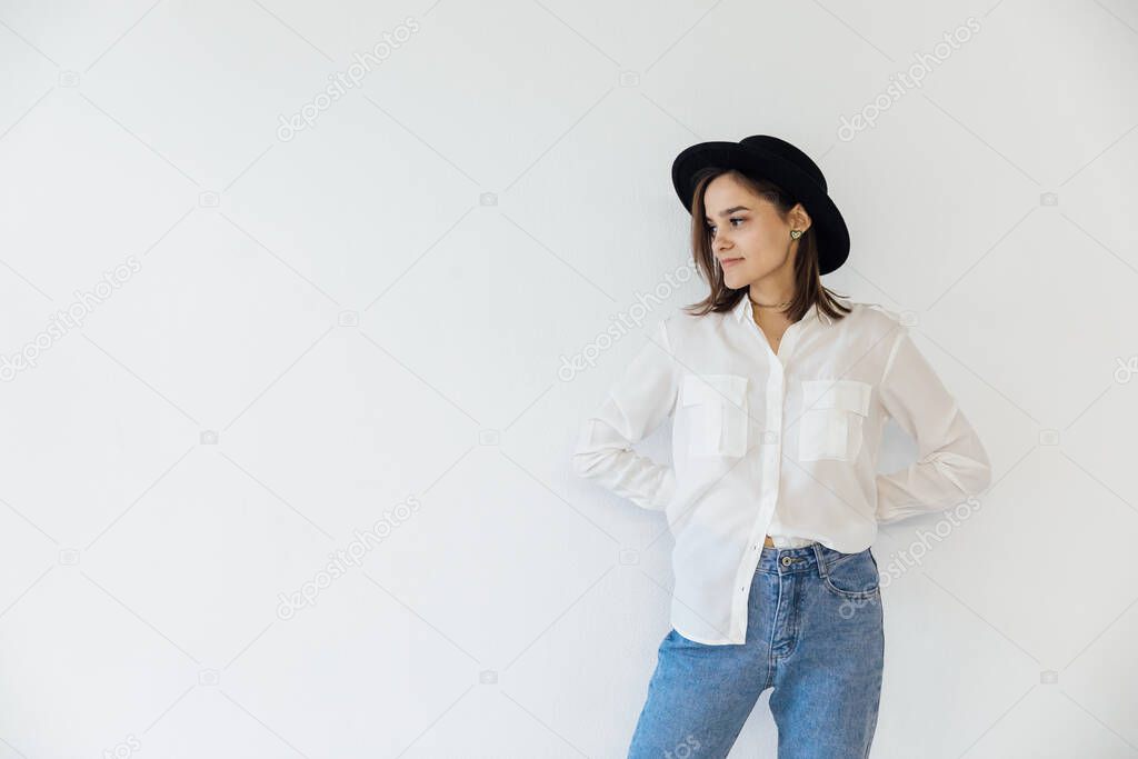 portrait of a beautiful fashionable young woman in jeans and a black hat