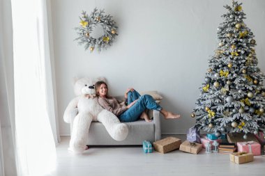 Beyaz Noel ağacının yanındaki kanepede yeni yıl hediyeleriyle güzel bir kadın.