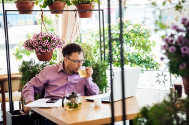 Restoranda engelli bir adam dizüstü bilgisayarla çalışır.