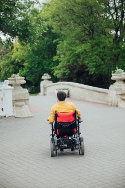 Tekerlekli sandalyeli engelli bir adam şehirde dolaşıyor.