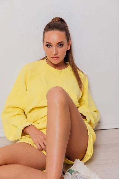 Bella donna in giallo abbigliamento sportivo su uno sfondo giallo — Foto Stock