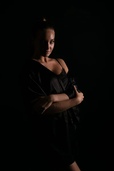 Portré egy gyönyörű nő fekete selyem fehérnemű a sötétben — Stock Fotó