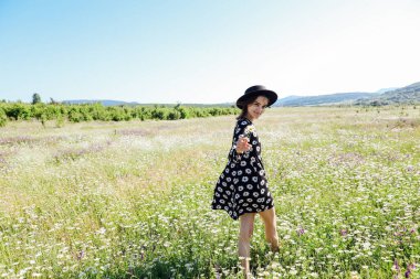 Güzel bir kadın papatya tarlasında yürüyor.